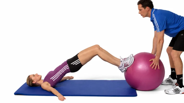 Assisted bridging: the coach steadies the ball while the athlete raises the hips with head and shoulders supported.