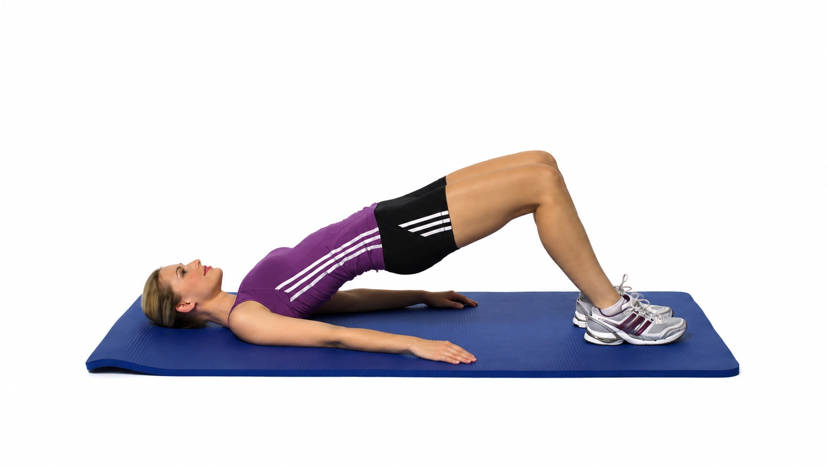 Supine Bridging: athlete holds a bridge with both feet on a blue mat against a white background.
